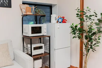 a kitchen with a microwave and a refrigerator at YJ-HOTEL kamiikebukuro 1F \u5317\u6c60\u888b5\u5206\u949f \u65b0\u88c5\u4e0a\u7ebf 52\u5e73\u65b9 in Tokyo