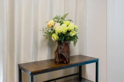 a vase of yellow roses sitting on a table at Kita-Akabane - Diamond Yu in Tokyo