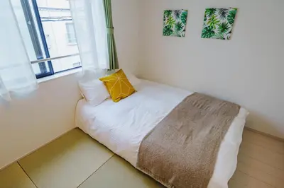 a bed with a yellow pillow on it in a room at QH202, Newly renovated hotel, direct access to Ueno, Asakusa, Disneyland, Airport in Tokyo