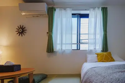 a bedroom with a bed and a window with green curtains at QH202, Newly renovated hotel, direct access to Ueno, Asakusa, Disneyland, Airport in Tokyo