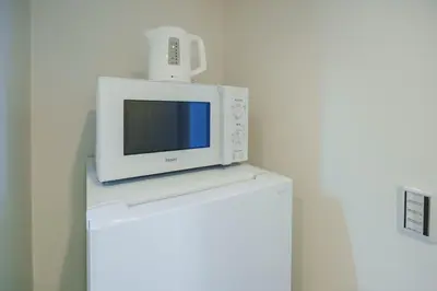 a white microwave sitting on top of a refrigerator at QH301, Newly renovated hotel, direct access to Ueno, Asakusa, Disneyland, Airport in Tokyo