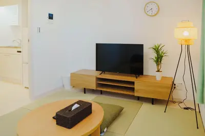 a living room with a flat screen tv on a wooden entertainment center at QH301, Newly renovated hotel, direct access to Ueno, Asakusa, Disneyland, Airport in Tokyo