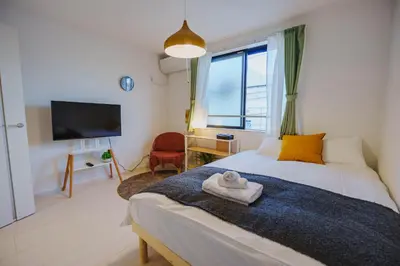 a bedroom with a bed with yellow pillows and a television at QH303, Newly renovated hotel, direct access to Ueno, Asakusa, Disneyland, Airport in Tokyo
