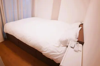 a bedroom with a white bed with a remote control at Tokyo Ikebukuro \u4e09\u5c42\u72ec\u680b\u522b\u58854\u5ba41\u53852\u536b2\u4e2a\u6d17\u6fa1\u95f4\u6c60\u888b\u99c5C1\u51fa\u53e3\u5f92\u6b657\u5206\u949f in Tokyo