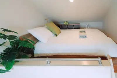 a small bedroom with a bed with white sheets and a plant at Home Story in Tokyo Kanametyo-Ikebukuro-Ginzaまで直通&東京屋語 in Tokyo