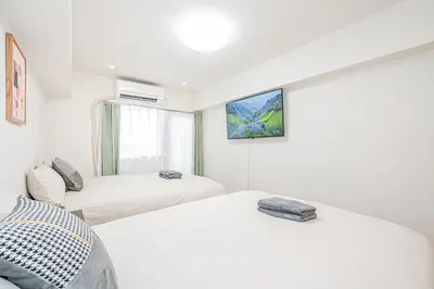 two beds in a white room with a painting on the wall at \u65b0\u5bbf\u5e02\u4e2d\u5fc3\u6b4c\u821e\u4f0e\u5ba2\u623f\u6e90\u51fa\u884c\u4fbf\u5229\u514d\u8d39Wi-Fi in Tokyo