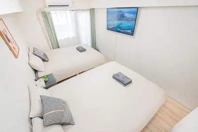 two beds in a small room with a window at \u65b0\u5bbf\u5e02\u4e2d\u5fc3\u6b4c\u821e\u4f0e\u5ba2\u623f\u6e90\u51fa\u884c\u4fbf\u5229\u514d\u8d39Wi-Fi in Tokyo