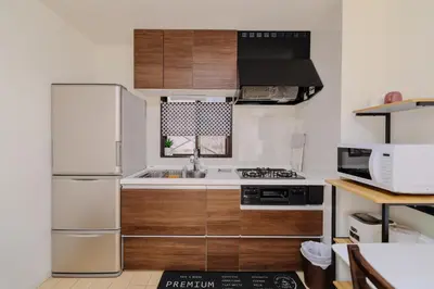 a kitchen with wooden cabinets and a white refrigerator at Iriya House \u5165\u8c37\u516c\u5bd3 801 in Tokyo