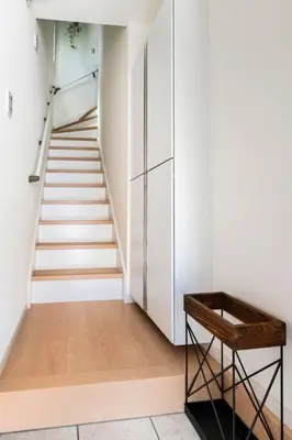 a hallway with a staircase with white walls and a chair at \u5343\u4f4f\u6cb3\u539f\u753a2f 3f in Tokyo