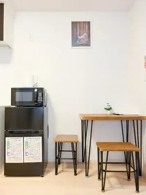 a table and a microwave and a table and two stools at Shinjuku Tokyo Holiday Hotel in Tokyo