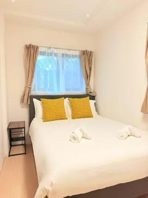 a bedroom with a white bed with yellow pillows and a window at Shinjuku Tokyo Holiday Hotel in Tokyo
