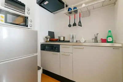a kitchen with white cabinets and a stove top oven at 203 Modern Comfort in Shinjuku Triple Station Access Free Wi-Fi in Tokyo