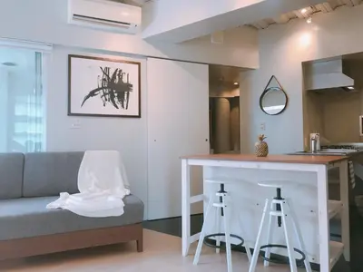a living room with a couch and a bar with stools at Fleg Higashi Azabu in Tokyo