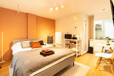 a bedroom with a bed and a table and a kitchen at FIKA Shibuya Honmachi 101 in Tokyo