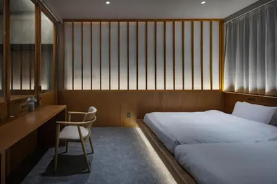 a bedroom with two beds and a desk and a chair at YUURO Bath-Living Hotel Ryogoku in Tokyo