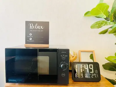 a microwave sitting on a table next to a clock at Alo BnB 12 - Game Universe - Easy Access to Shibuya - New ! in Tokyo