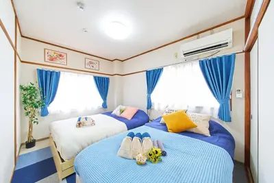two beds in a small room with blue curtains at Belmont 201 3min to Station Easy Access Ueno Asakusa Skytree Sleeps 5 in Tokyo