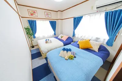 two beds in a small room with blue curtains at Belmont 201 3min to Station Easy Access Ueno Asakusa Skytree Sleeps 5 in Tokyo