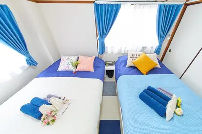 two beds in a small room with blue curtains at Belmont 201 3min to Station Easy Access Ueno Asakusa Skytree Sleeps 5 in Tokyo
