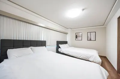 a bedroom with two beds with white sheets at \u6e0b\u8c37\u99c5\u96fb\u8eca1\u5206 \u6075\u6bd4\u5bff\u99c5\u5f92\u6b692\u5206 85\u5e73\u7c73\u6700\u59276\u540d \u6771\u4eac \u65b0\u5bbf \u4e0a\u91ce \u9280\u5ea7 \u6c60\u888b \u7bc9\u5730\u76f4\u901a in Tokyo