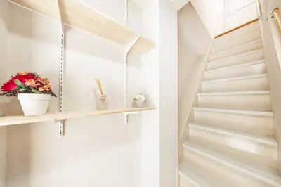 a white staircase with a shelf and flowers at NewOpen! \u99c5\u5f92\u6b691\u5206 \u6c60\u888b\u30a8\u30ea\u30a2 60\u5e73\u7c73\u6700\u59278\u540d\u5bbf\u6cca\u53ef\u80fd \u548c\u98a8\u30e2\u30c0\u30f3 in Tokyo