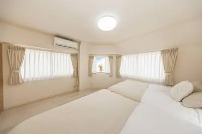 a bedroom with two white beds and two windows at NewOpen! \u99c5\u5f92\u6b691\u5206 \u6c60\u888b\u30a8\u30ea\u30a2 60\u5e73\u7c73\u6700\u59278\u540d\u5bbf\u6cca\u53ef\u80fd \u548c\u98a8\u30e2\u30c0\u30f3 in Tokyo