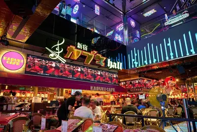 a restaurant with people sitting at tables and neon signs at \u65b0\u5bbf\u6b4c\u821e\u4f0e\u753a\u7acb\u5730\u6700\u9ad83\u30d9\u30c3\u30c9 in Tokyo