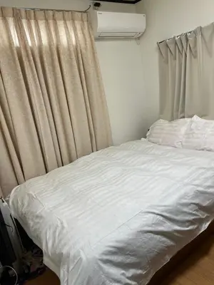 a bed with white sheets in a room with a window at \u897f\u6c60\u888b\u4e4b\u5bb6 in Tokyo