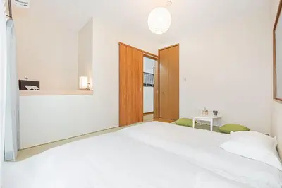 a bedroom with a large white bed and a table at Tomo house in Tokyo