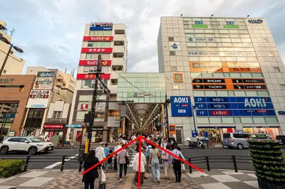 a group of people walking down a street with a red ribbon at Tomo house in Tokyo