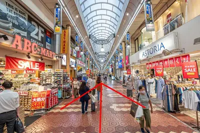 a group of people walking through a shopping mall at Tomo house in Tokyo