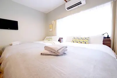 a white bedroom with two beds and a window at Yoyogi Flats - Vacation STAY 17486 in Tokyo