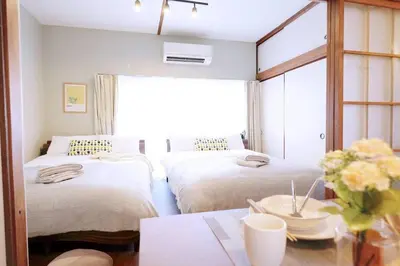 a bedroom with two beds and a table with a vase of flowers at Yoyogi Flats - Vacation STAY 17486 in Tokyo