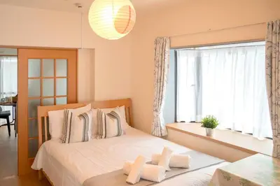 a bedroom with a bed with white pillows and a window at \u65b0\u5bbf\u4e00\u7ad95\u5206\u949f-104-\u9910\u9986\u8d2d\u7269\u8857-\u5b89\u9759\u54c1\u8d28\u516c\u5bd3-\u76f4\u8fbe\u7687\u5c45\u79cb\u53f6\u539f in Tokyo