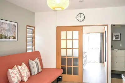 a living room with a couch and a clock on the wall at \u65b0\u5bbf\u4e00\u7ad95\u5206\u949f-204-\u9910\u9986\u8d2d\u7269\u8857-\u5b89\u9759\u54c1\u8d28\u516c\u5bd3-\u76f4\u8fbe\u7687\u5c45\u79cb\u53f6\u539f in Tokyo