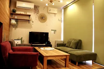 a living room with two chairs and a table and a tv at Rakuna Inn \u6cb3 Oshiage in Tokyo
