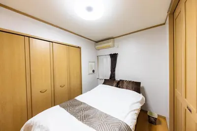 a small bedroom with two beds and wooden cabinets at NOT A HOME\u4e80\u6709 \u99c5\u5f92\u6b695\u5206 \u7121\u6599\u99d0\u8eca\u5834 \u30c7\u30a3\u30ba\u30cb\u30fc\u307e\u3067\u8eca22\u5206 \u7fbd\u7530\u7a7a\u884c\u30d0\u30b9\u76f4\u901a 90m2 in Tokyo