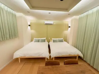 two beds in a small room with green curtains at \u82b1\u5bbf\u6d45\u8349\u4e8c\u756a Hanayado Asakusa2 in Tokyo