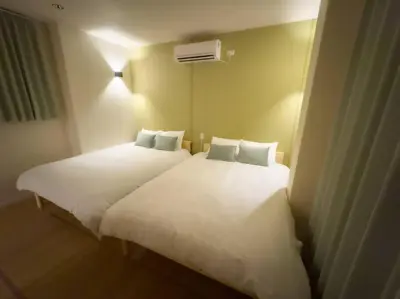 a bedroom with two beds with white sheets at \u82b1\u5bbf\u6d45\u8349\u4e8c\u756a Hanayado Asakusa2 in Tokyo
