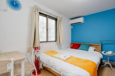 a bedroom with a bed and a blue wall at \u5343\u4f4f\u5bff\u753a1f in Tokyo