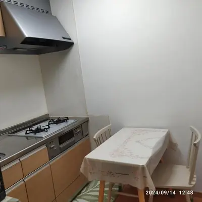 a small kitchen with a stove and a table with a stool at kyoka house\u6c60\u888b\u81f3\u8fd1 in Tokyo