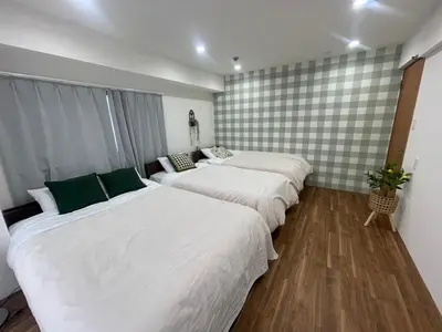 a room with three beds with white sheets and green pillows at HARMONIa\u6771\u4eac\u5800\u5207202 in Tokyo