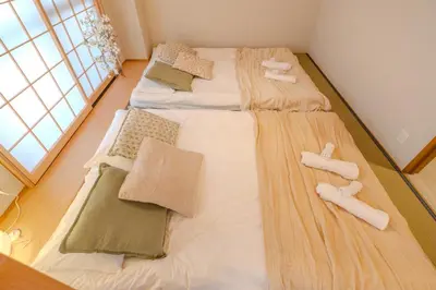 two twin beds in a room with a large window at Six7 APT\u4e09\u30ce\u8f2a in Tokyo