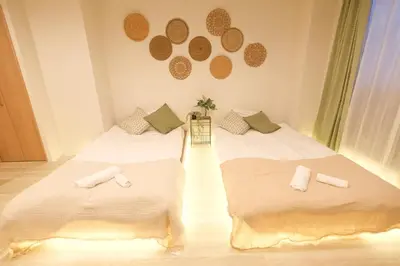 a bedroom with two beds with white sheets at Six7 APT\u4e09\u30ce\u8f2a in Tokyo