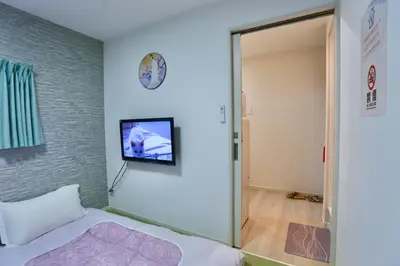 a bedroom with a bed and a tv on the wall at Mizuken Home in Tokyo