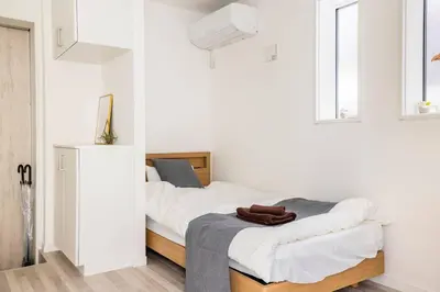 a bedroom with a bed with white walls and windows at \u65b0\u4e951\u4e01\u76ee in Tokyo