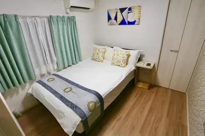 a small bedroom with a bed with green curtains at MIZUKEN Home With Living Room And Sofa Bed in Tokyo