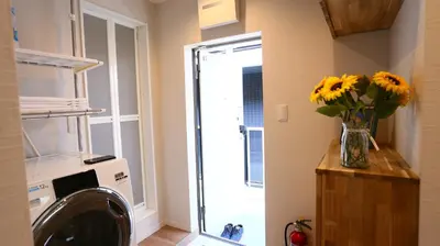 a laundry room with a washing machine and a vase of yellow flowers at MIZUKEN Home With Living Room And Sofa Bed in Tokyo