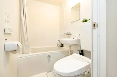 a white bathroom with a toilet and a sink at FIKA Shibuya Honmachi 102 in Tokyo