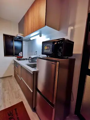 a kitchen with a microwave on top of a refrigerator at \u4e09\u30ce\u8f2a201 in Tokyo